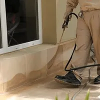 General pest control technician spraying exterior perimeter around a home in Riverside, CA