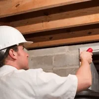 Termite inspection technician checking a basement wall and framing for termite activity in Riverside, CA